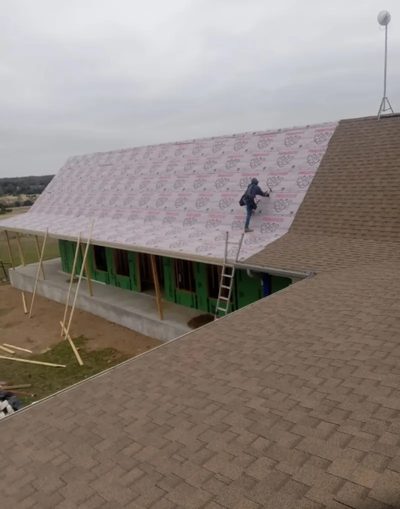 Worker preparing underlayment for a metal roof installation in Fontana